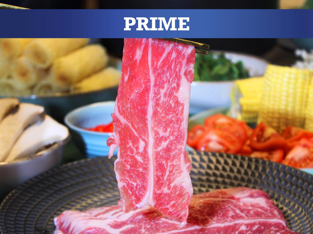 Raw beef with a 'PRIME' label in front of a variety of food items on a table.